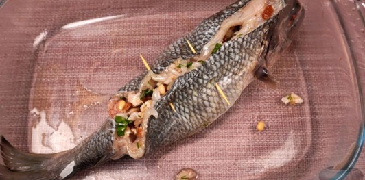 Фото приготовления рецепта: Фаршированная дорада с изюмом и орехами, запечённая со сладким перцем - шаг №17