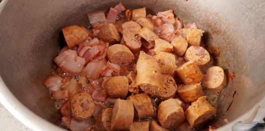 Фото приготовления рецепта: Свинина, тушенная с овощами, беконом и копчёными колбасками (по-дебреценски) - шаг №10